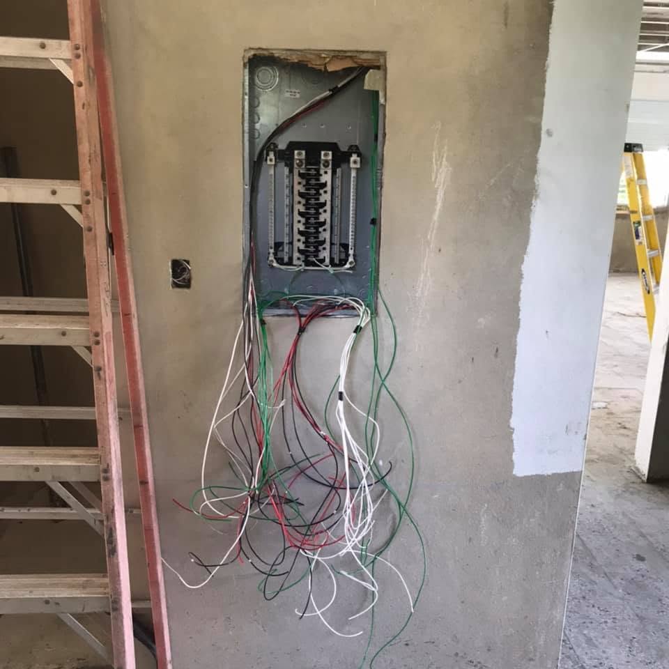 Centro de carga empotrado en pared con conductores ramales a la espera de conexión.