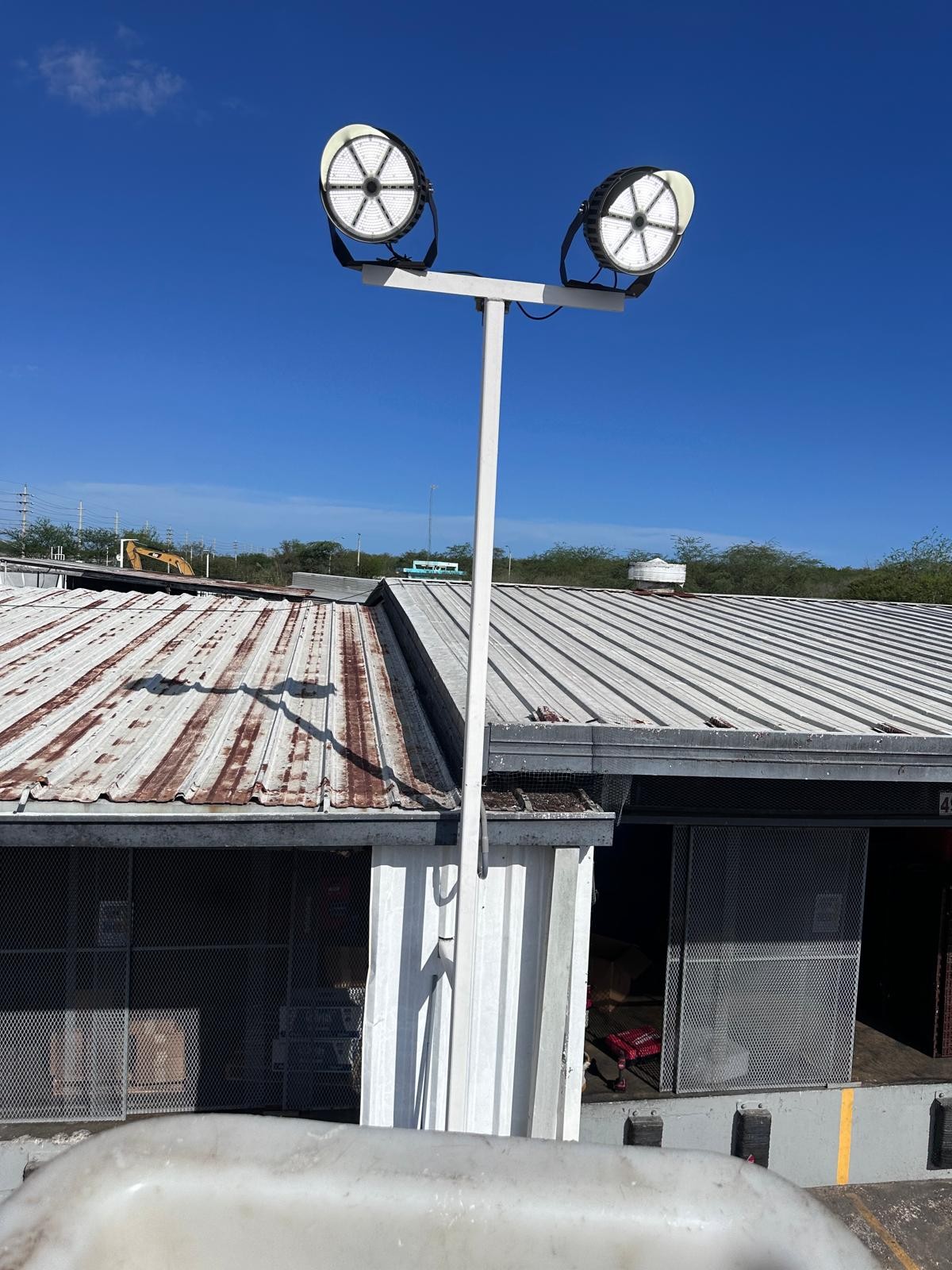 Par de reflectores LED montados sobre poste, vistos desde la canasta del camión durante la instalación.